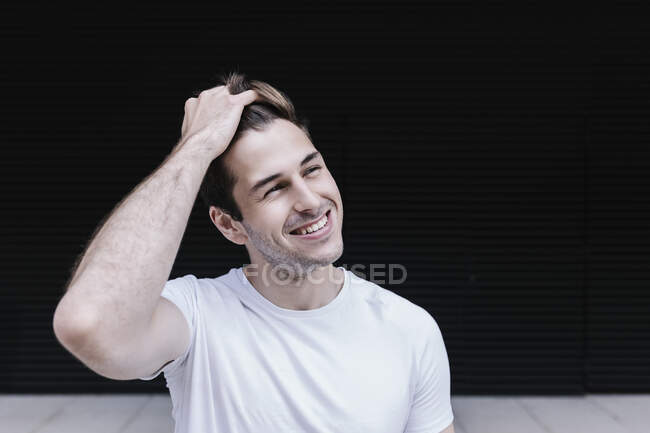 Uomo sorridente con la mano nei capelli distogliendo lo sguardo — Foto stock