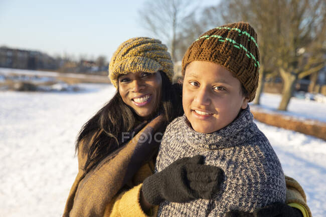 Sorridente madre e figlio indossano cappello a maglia in piedi insieme durante l'inverno — Foto stock