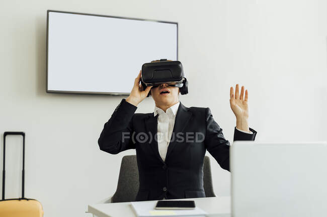 Зріла жінка-професіонал дивиться симулятор віртуальної реальності, сидячи за столом у офісі. — стокове фото