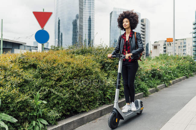 Young woman riding electric push scooter in city — Stock Photo
