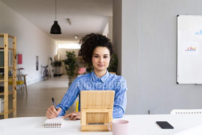 Businesswoman with note pad and digital tablet in creative office — Stock Photo