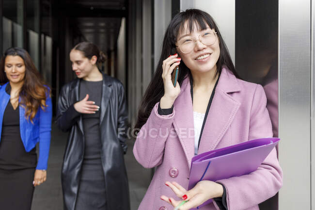 Imprenditrice donna che parla sul cellulare con colleghi in background — Foto stock