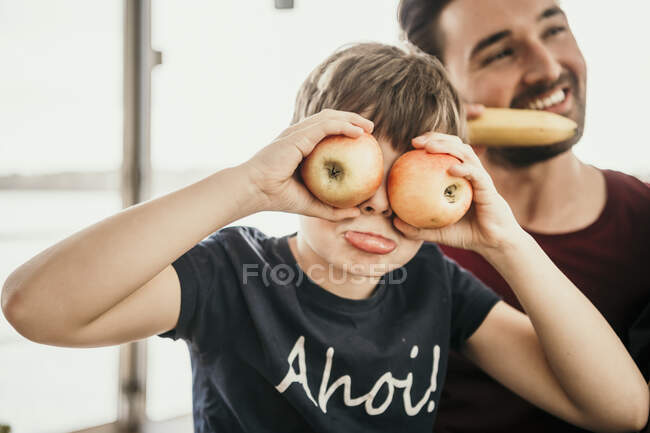 Ragazzo giocoso che copre gli occhi con le mele — Foto stock