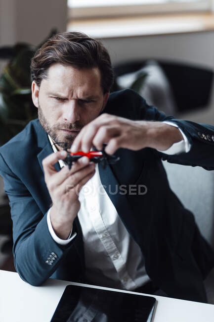 Businessman checking drone while siting at office — Stock Photo