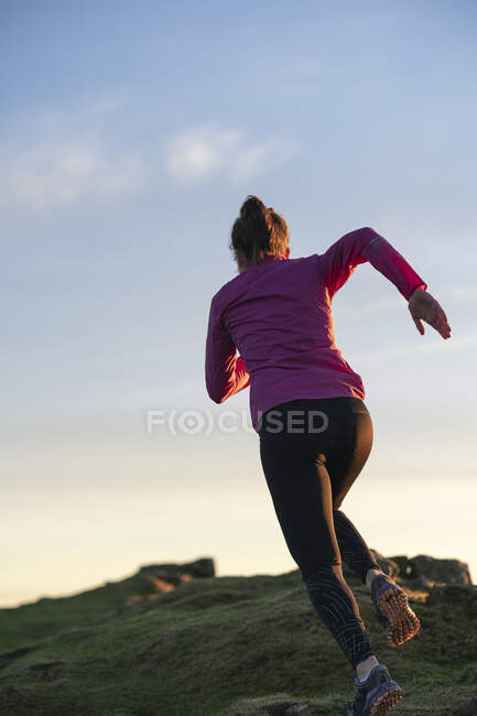Junge Frau rennt bei Sonnenaufgang auf Hügel — Stockfoto