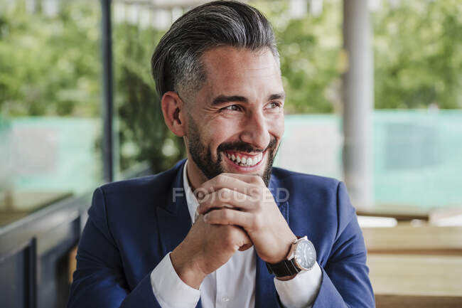 Cheerful businessman with hand on chin looking away at cafeteria — Stock Photo