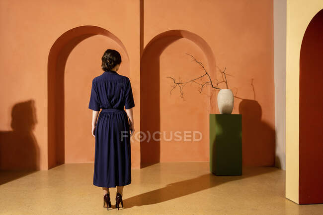 Mulher em pé na frente da parede laranja com arcos — Fotografia de Stock