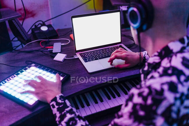 Compositeur masculin portant des écouteurs à l'aide d'un ordinateur portable et tablette numérique en studio — Photo de stock