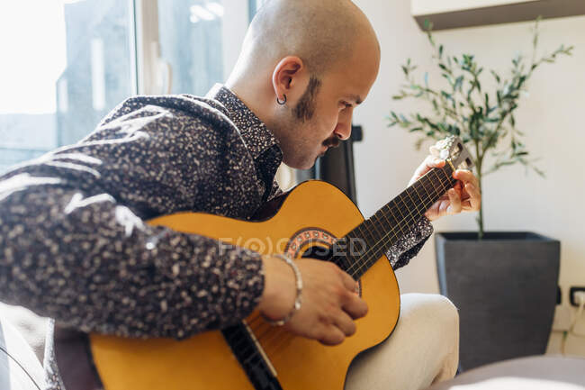 Homme jouant de la guitare à la maison — Photo de stock