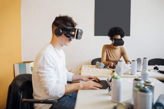 Young multi ethnic couple wearing virtual reality simulator while working in studio — Stock Photo