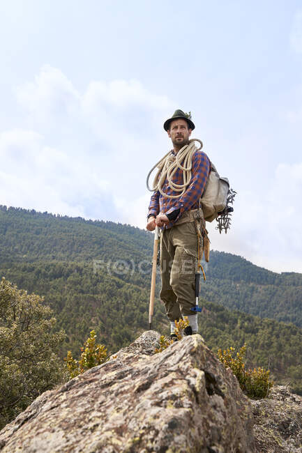 Мужчина альпинист с рюкзаком и снаряжением, стоящим на горе — стоковое фото