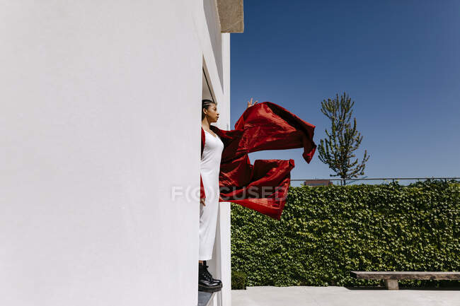 Mujer joven con abrigo rojo de pie en la puerta - foto de stock