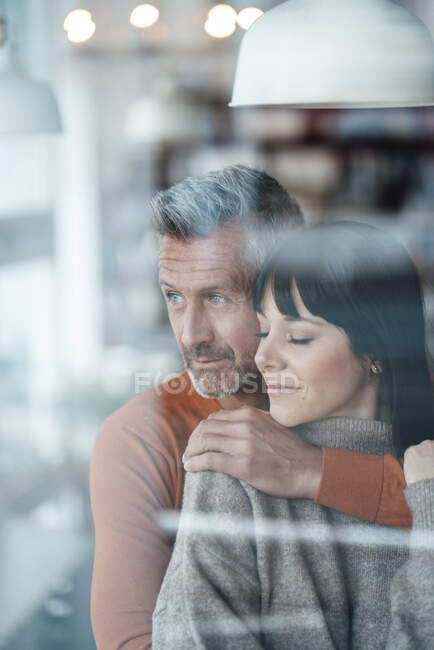 Man with arm around on woman looking away at cafe — Stock Photo