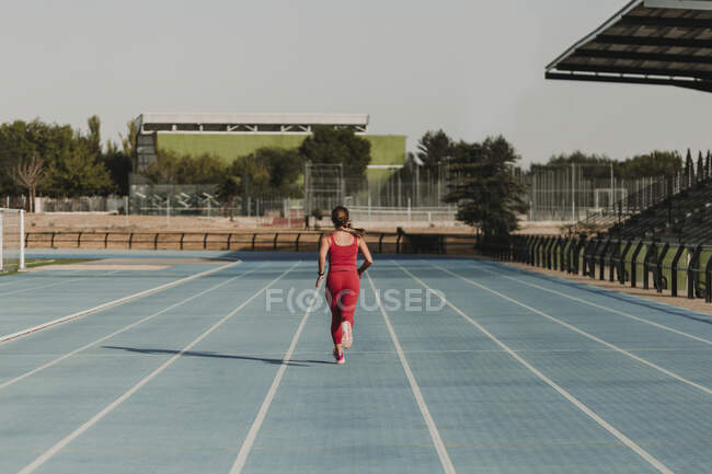 Active female athlete running on sports track at stadium — Stock Photo