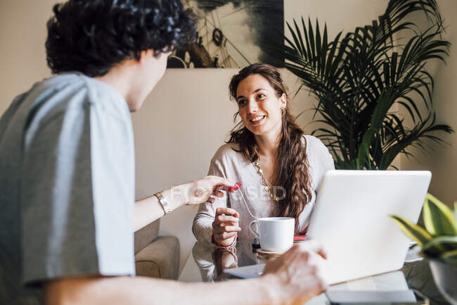 Smiling girlfriend talking to boyfriend while having coffee at home — Stock Photo