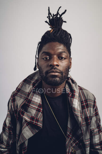 Hombre joven con el peinado locs de pie delante de fondo blanco - foto de stock