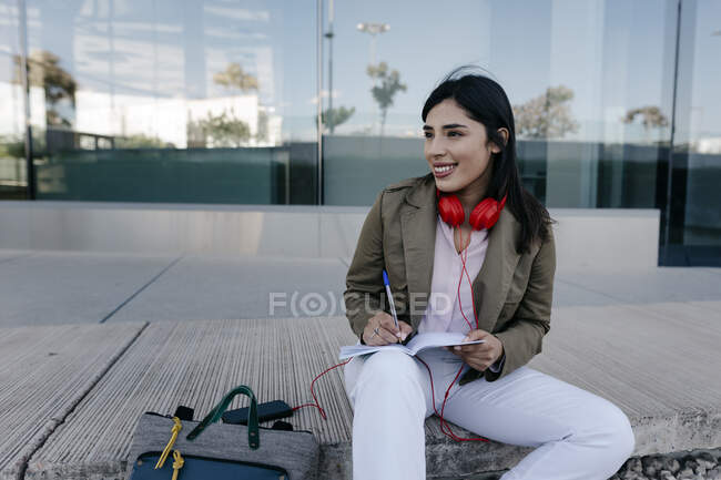 Femme souriante assis professionnel avec livre sur le sentier — Photo de stock