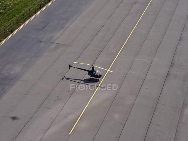 Aerial view of Robinson R22 helicopter standing in middle of empty airport runway — Stock Photo