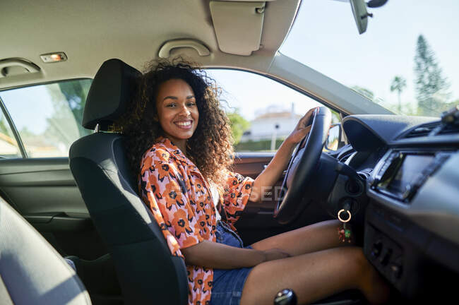 Femme souriante assise en voiture le jour ensoleillé — Photo de stock