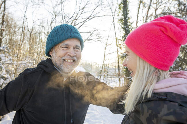 Усміхнений чоловік в теплому одязі дивиться на жінку взимку — стокове фото