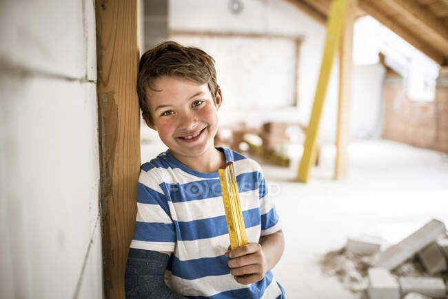 Sorrindo menino segurando fita métrica durante a renovação da casa — Fotografia de Stock