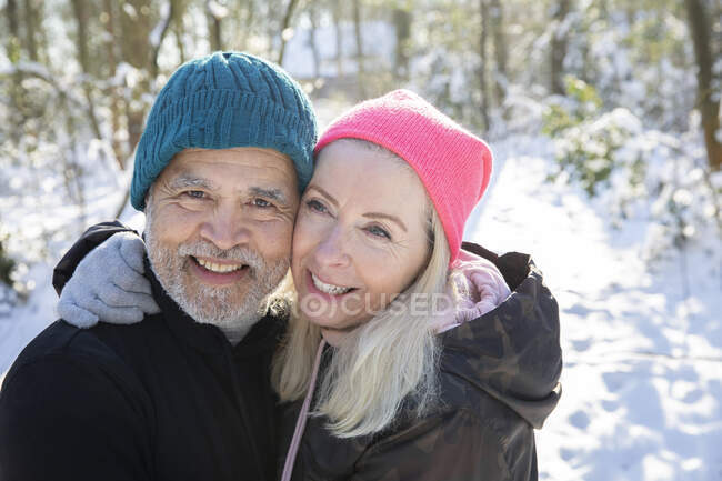 Старшая пара с улыбкой щеки к щеке в лесу — стоковое фото