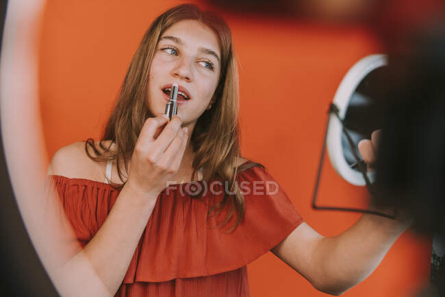 Female influencer applying lipstick while vlogging make-up tutorial at home — Stock Photo