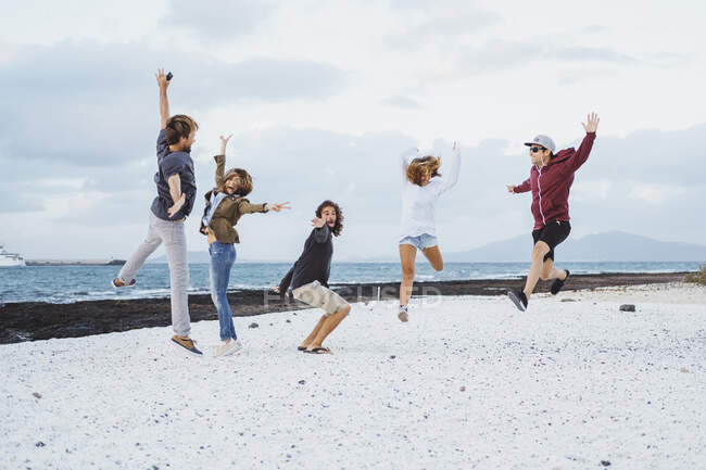 Amici spensierati che saltano in spiaggia — Foto stock