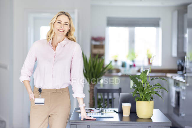 Donna d'affari con mano in tasca in piedi vicino alla scrivania a casa ufficio — Foto stock