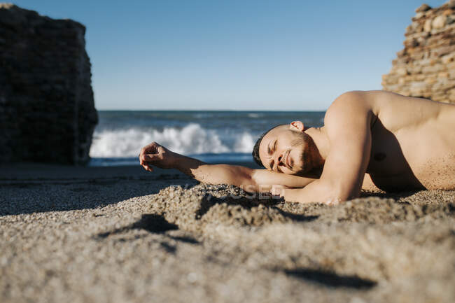 Безсоромна людина відпочиває, лежачи на березі. — стокове фото