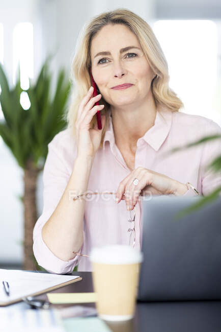 Feminino profissional falando no telefone inteligente em casa escritório — Fotografia de Stock