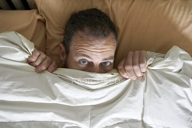 Mann deckt Gesicht mit Decke im Bett ab — Stockfoto