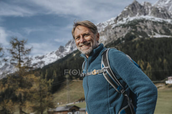 Sorrindo homem maduro com mochila de pé contra o céu em Hochkonig, Salzburger Land, Áustria — Fotografia de Stock