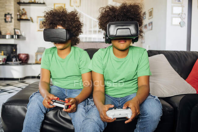 Irmãos gêmeos jogando jogo usando óculos de realidade virtual em casa — Fotografia de Stock