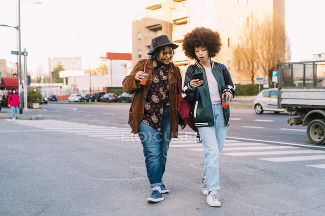 Young women using mobile phone while walking on phone — Stock Photo