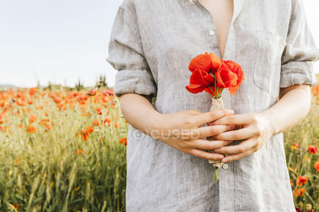 Поміж дорослої жінки, яка носить сорочку з маковими квітками на полі. — стокове фото