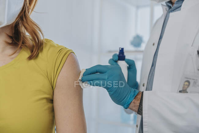 Médecin nettoyer les muscles du patient tout en se préparant à la vaccination en salle d'examen — Photo de stock