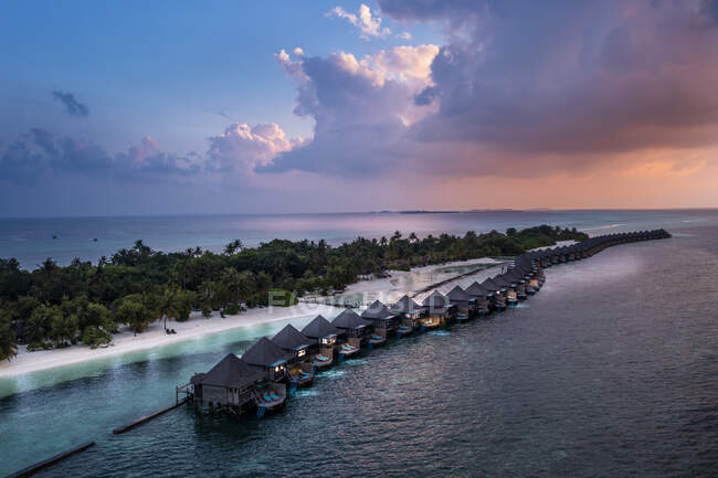 Casas inclinadas por mar en la isla de Kuredu durante el atardecer, Maldivas, Asia - foto de stock