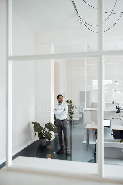 Male entrepreneur with arms crossed standing in office — Stock Photo