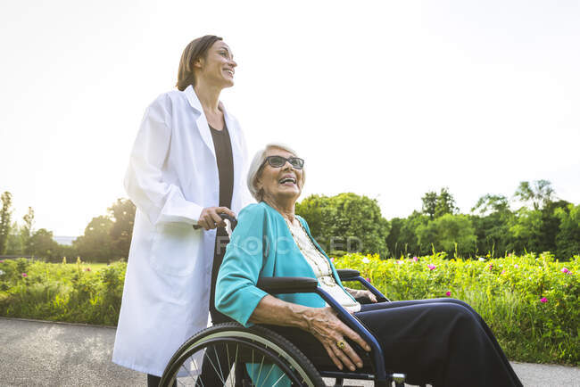 Femme âgée souriante avec gardien dans un parc public — Photo de stock