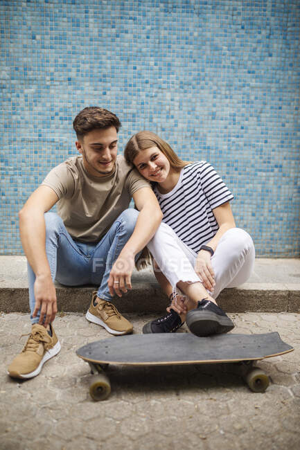 Sorrindo casal com skate sentado no caminho — Fotografia de Stock