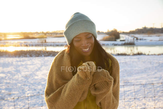 Fröhliche reife Frau mit blauer Strickmütze, die im Winter auf Schnee steht — Stockfoto