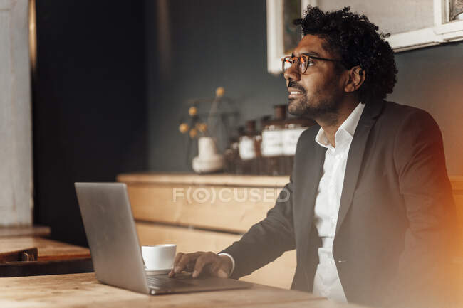 Uomo imprenditore con computer portatile seduto a tavola nel caffè — Foto stock