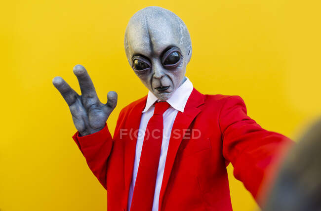 Retrato del hombre con traje alienígena y traje rojo brillante que se extiende hacia la cámara - foto de stock