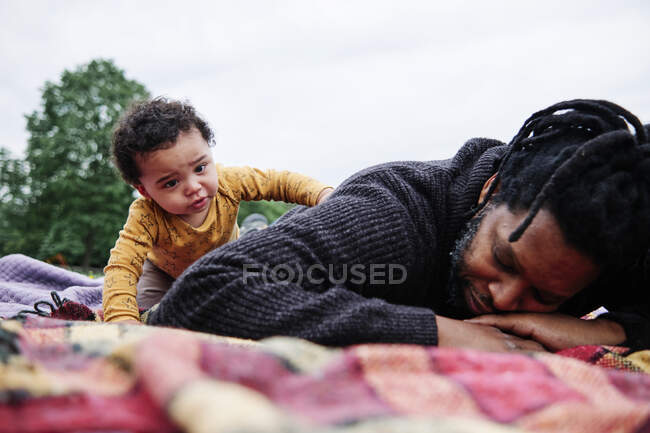 Hijo preocupado mirando a padre acostado en una manta de picnic en el  parque — estilo de vida, Niños pequeños - Stock Photo | #495968276