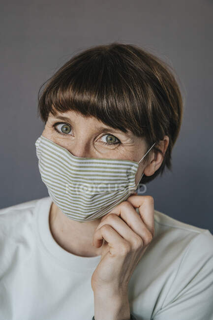 Femme adulte moyenne avec masque protecteur sur fond gris — Photo de stock