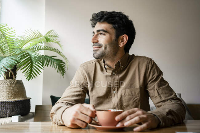 Sorrindo homem com xícara de café sentado no restaurante — Fotografia de Stock