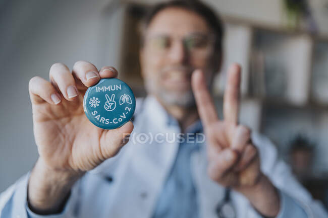 Medico tenendo distintivo segno mano mentre in piedi in clinica — Foto stock