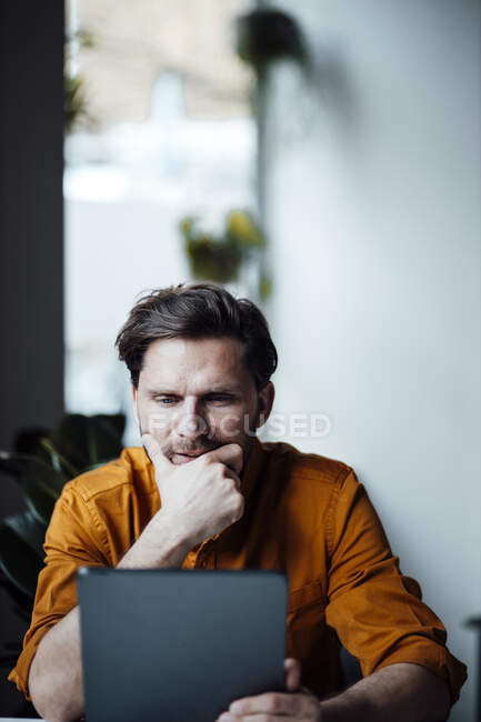 Male entrepreneur contemplating while using digital tablet in office — Stock Photo