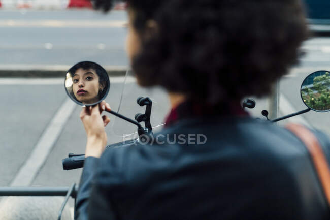 Frau blickt in Seitenspiegel von Motorroller — Stockfoto